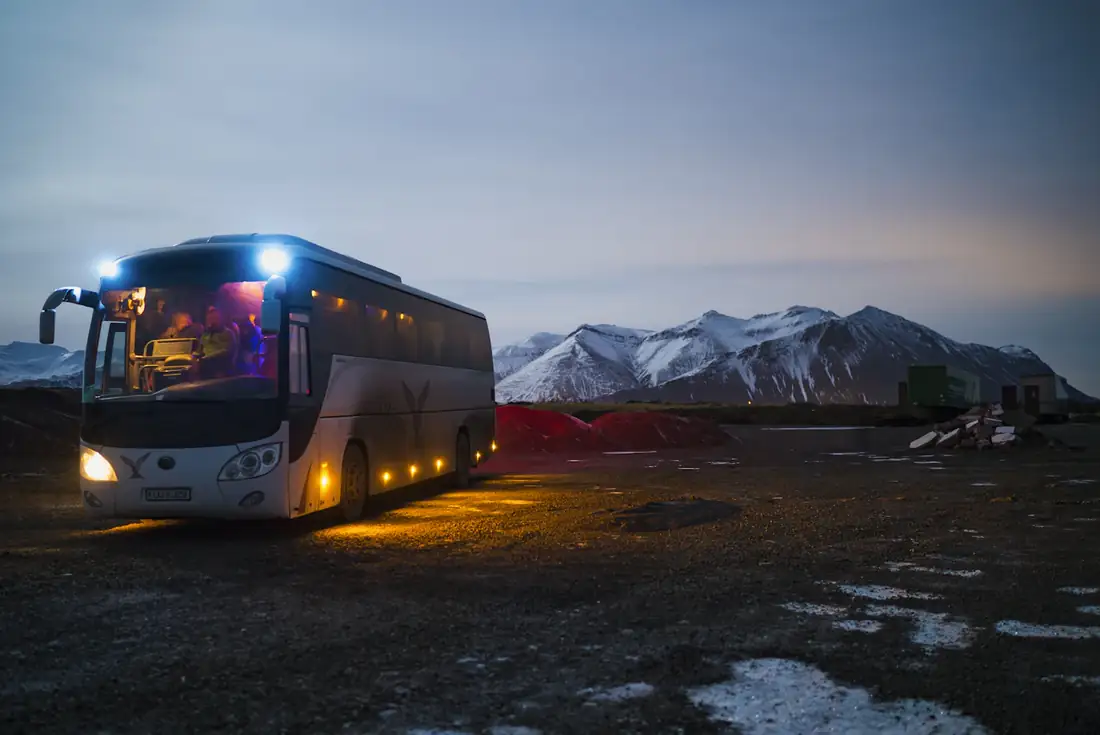 Tourist coach below snowy mountains